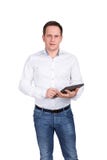 Успешный молодой бизнесмен на белой предпосылке в белой рубашке и голубых джинсах держит прибор таблетки в его руках Стоковая Фотография RF Успешный молодой бизнесмен на белой предпосылке в белой рубашке и голубых джинсах держит прибор таблетки в его руках Стоковая Фотография RF