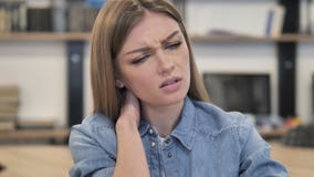 Уставшая творческая женщина с болью шеи, ослабляя Уставшая творческая женщина с болью шеи, ослабляя