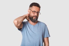 Утомлянная unemotional красивая исполнительная власть смотрит твердо на камере, держащ его руку позади, делающ массаж шеи после т стоковое фото rf Утомлянная unemotional красивая исполнительная власть смотрит твердо на камере, держащ его руку позади, делающ массаж шеи после т стоковое фото rf