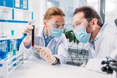 ученые в белых пальто и медицинских масках работая с реагентами стоковое фото rf ученые в белых пальто и медицинских масках работая с реагентами стоковое фото rf