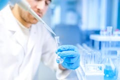 Ученый используя медицинский инструмент для извлечения жидкости от образцов в специальной лаборатории или медицинской комнате Ученый используя медицинский инструмент для извлечения жидкости от образцов в специальной лаборатории или медицинской комнате