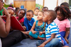 Учитель читая книгу с классом детей дошкольного возраста стоковые изображения Учитель читая книгу с классом детей дошкольного возраста стоковые изображения
