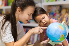 Учитель и preschool студент уча землеведение на глобусе мира стоковые изображения rf Учитель и preschool студент уча землеведение на глобусе мира стоковые изображения rf