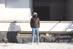 Фасонируйте стильного молодого африканского человека стоя носящ куртку с связанной шляпой, стилем улицы зимы стоковая фотография rf Фасонируйте стильного молодого африканского человека стоя носящ куртку с связанной шляпой, стилем улицы зимы стоковая фотография rf