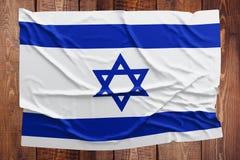 Флаг Израиля на предпосылке деревянного стола Сморщенный израильский взгляд сверху флага стоковая фотография Флаг Израиля на предпосылке деревянного стола Сморщенный израильский взгляд сверху флага стоковая фотография