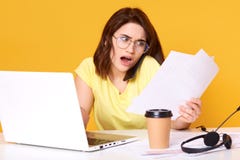 Фото напряженной молодой бизнес-леди брюнета работая с печатными документами в офисе над желтой предпосылкой, проверяя стоковые фото Фото напряженной молодой бизнес-леди брюнета работая с печатными документами в офисе над желтой предпосылкой, проверяя стоковые фото