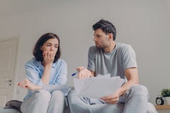 Фото напряженных молодых пар семьи имеет много задолженностей, подготавливает fincial отчет, думает о превращаться будущего их де стоковое изображение rf Фото напряженных молодых пар семьи имеет много задолженностей, подготавливает fincial отчет, думает о превращаться будущего их де стоковое изображение rf
