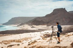 Фотограф с камерой в пустыне впуская уникально ландшафт скал песчанных дюн вулканических на атлантическом побережье Baia стоковое изображение rf Фотограф с камерой в пустыне впуская уникально ландшафт скал песчанных дюн вулканических на атлантическом побережье Baia стоковое изображение rf
