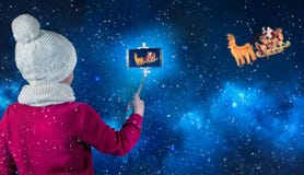 Фотоснимки мальчика Санта Клауса в санях с северным оленем который летает через небо стоковые фотографии rf Фотоснимки мальчика Санта Клауса в санях с северным оленем который летает через небо стоковые фотографии rf