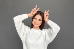 фристайл Положение маленькой девочки изолированное на серых показывая рожках усмехаясь шаловливый конец--вверх стоковое фото фристайл Положение маленькой девочки изолированное на серых показывая рожках усмехаясь шаловливый конец--вверх стоковое фото