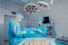 Хирурги объединяются в команду работа с контролем пациента в хирургической операционной Увеличение груди стоковые фото Хирурги объединяются в команду работа с контролем пациента в хирургической операционной Увеличение груди стоковые фото