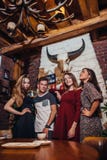 4 холодных подростка нося вскользь одежды представляя для камеры в стильном с дизайном интерьера охотничьего домика Стоковые Изображения 4 холодных подростка нося вскользь одежды представляя для камеры в стильном с дизайном интерьера охотничьего домика Стоковые Изображения