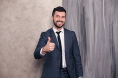 Хороший выглядя красивый счастливый бизнесмен стоит в его офисе показ стоковое изображение rf Хороший выглядя красивый счастливый бизнесмен стоит в его офисе показ стоковое изображение rf