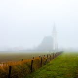 Церковь вертепа Hoorn на туманном утре осени на острове Texel в Нидерланд стоковые изображения rf Церковь вертепа Hoorn на туманном утре осени на острове Texel в Нидерланд стоковые изображения rf