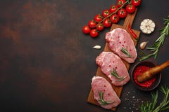 Части сырцового стейка свинины с базиликом, томатами вишни, розмариновым маслом, чесноком, перцем, минометом соли и специи на раз стоковое фото rf Части сырцового стейка свинины с базиликом, томатами вишни, розмариновым маслом, чесноком, перцем, минометом соли и специи на раз стоковое фото rf