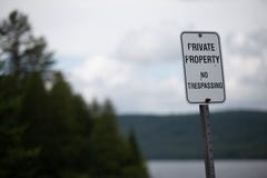 Частная собственность отсутствие Trespassing знака перед лесом и озером стоковая фотография rf Частная собственность отсутствие Trespassing знака перед лесом и озером стоковая фотография rf