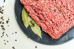 Часть сочного свежего семенить мяса на черной плите на деревянном столе с перцем и лист залива Взгляд сверху стоковое изображение rf Часть сочного свежего семенить мяса на черной плите на деревянном столе с перцем и лист залива Взгляд сверху стоковое изображение rf