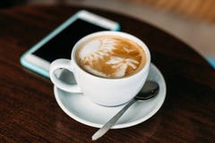 Чашка горячего кофе искусства latte на деревянном столе стоковые изображения Чашка горячего кофе искусства latte на деревянном столе стоковые изображения