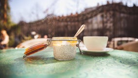 Чашка кофе и десерт с семенами chia в стеклянном опарнике на таблице в кафе снаружи стоковые фото Чашка кофе и десерт с семенами chia в стеклянном опарнике на таблице в кафе снаружи стоковые фото