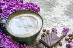 Чашка кофе утра с фиолетовыми цветками и шоколадом сирени Стоковые Фото Чашка кофе утра с фиолетовыми цветками и шоколадом сирени Стоковые Фото