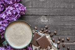 Чашка кофе утра с фиолетовыми цветками и шоколадом сирени Стоковые Изображения RF Чашка кофе утра с фиолетовыми цветками и шоколадом сирени Стоковые Изображения RF
