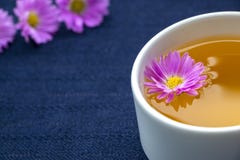 Чашка чая и фиолетовые цветки на темно-синей предпосылке скатерти стоковое фото rf Чашка чая и фиолетовые цветки на темно-синей предпосылке скатерти стоковое фото rf