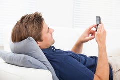 Человек используя умный телефон на софе Человек используя умный телефон на софе