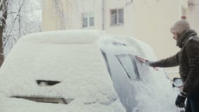 Человек освобождает снег от его автомобиля на улице в зиме, заднем взгляде, видеоматериал Человек освобождает снег от его автомобиля на улице в зиме, заднем взгляде, видеоматериал