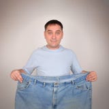 Человек потери веса держа большие брюки стоковые фотографии rf Человек потери веса держа большие брюки стоковые фотографии rf