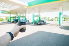 Человек при кофейная чашка идя к его автомобилю на бензоколонке стоковые фотографии rf Человек при кофейная чашка идя к его автомобилю на бензоколонке стоковые фотографии rf