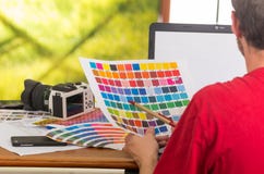 Человек работая на компьтер-книжке пока задерживающ pantone стоковое изображение Человек работая на компьтер-книжке пока задерживающ pantone стоковое изображение