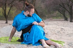 Человек Aughing красивый бородатый в голубом кимоно сидя на половике и смотря прочь стоковые изображения Человек Aughing красивый бородатый в голубом кимоно сидя на половике и смотря прочь стоковые изображения