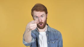 Человек Redhead указывая на камеру, желтую предпосылку Человек Redhead указывая на камеру, желтую предпосылку