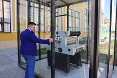 Человек в голубом костюме смотрит печатный станок за стеклом стоковая фотография rf Человек в голубом костюме смотрит печатный станок за стеклом стоковая фотография rf