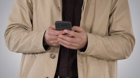 Человек в пальто канавы используя мобильный умный телефон на предпосылке градиента стоковое фото Человек в пальто канавы используя мобильный умный телефон на предпосылке градиента стоковое фото