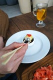 Человек ест суши в черной плите на деревянном столе, конец-вверх Rolls стоковая фотография Человек ест суши в черной плите на деревянном столе, конец-вверх Rolls стоковая фотография