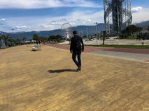 Человек идет вдоль прогулки на улице в тропическом теплом курорте рая на предпосылке зеленых пальм стоковое фото rf Человек идет вдоль прогулки на улице в тропическом теплом курорте рая на предпосылке зеленых пальм стоковое фото rf