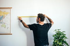 Человек измеряет стену с измеряя лентой стоковая фотография Человек измеряет стену с измеряя лентой стоковая фотография
