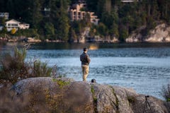 Человек летает его трутень над океаном на парк Whytecliff , Западный Ванкувер стоковое изображение rf Человек летает его трутень над океаном на парк Whytecliff , Западный Ванкувер стоковое изображение rf