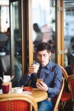 Человек с кофе и смартфоном стоковая фотография Человек с кофе и смартфоном стоковая фотография