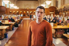 Человек студента Intelegent в стеклах стоит публично читальный зал библиотеки стоковые фото Человек студента Intelegent в стеклах стоит публично читальный зал библиотеки стоковые фото