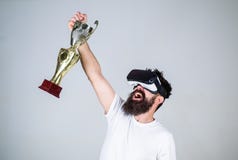 Чемпионат онлайн Шлемофон vr битника человека бородатый держит золотой кубок Победа чувства в играх виртуальной реальности достиг стоковое изображение rf Чемпионат онлайн Шлемофон vr битника человека бородатый держит золотой кубок Победа чувства в играх виртуальной реальности достиг стоковое изображение rf