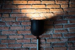Черная лампа со светом на текстуре кирпичной стены стоковое фото Черная лампа со светом на текстуре кирпичной стены стоковое фото