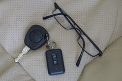 Черно-снабженные ободком стекла и ключи автомобиля лежа на стуле в эко-коже стоковые фото Черно-снабженные ободком стекла и ключи автомобиля лежа на стуле в эко-коже стоковые фото