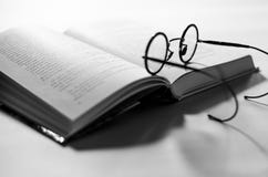 Чернота вокруг старых стекел кладет на открытую белую книгу, которая лежит на белой предпосылке стоковые изображения rf Чернота вокруг старых стекел кладет на открытую белую книгу, которая лежит на белой предпосылке стоковые изображения rf
