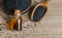 Черные семена и эфирное масло тимона с шаром и деревянными лопаткоулавливателем или ложкой стоковые изображения rf Черные семена и эфирное масло тимона с шаром и деревянными лопаткоулавливателем или ложкой стоковые изображения rf