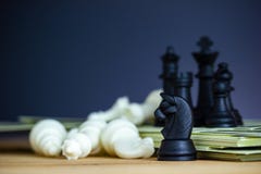 Черные шахматы стоят поверх банкнот доллара стоковые фотографии rf Черные шахматы стоят поверх банкнот доллара стоковые фотографии rf