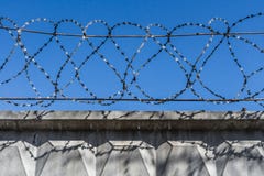 Черный затрапезный колючий провод металла на проводах на загородке против голубого неба стоковая фотография rf Черный затрапезный колючий провод металла на проводах на загородке против голубого неба стоковая фотография rf