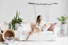 Чувственная и красивая белокурая модельная девушка в модных стеклах и стильных пижамах сатинировки, сидит на белой софе с подушка стоковые изображения rf Чувственная и красивая белокурая модельная девушка в модных стеклах и стильных пижамах сатинировки, сидит на белой софе с подушка стоковые изображения rf