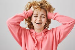Чувствовать беспечальный и счастливый Портрет эмотивной молодой женщины с скручиваемостями, вытягивающ волосы ОН назад при руки, стоковая фотография Чувствовать беспечальный и счастливый Портрет эмотивной молодой женщины с скручиваемостями, вытягивающ волосы ОН назад при руки, стоковая фотография